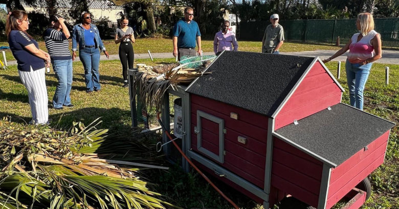 A group of students standing around a demonstration coop at the University of Florida's Institute of Farming and Agriculture Studies Extension Office.